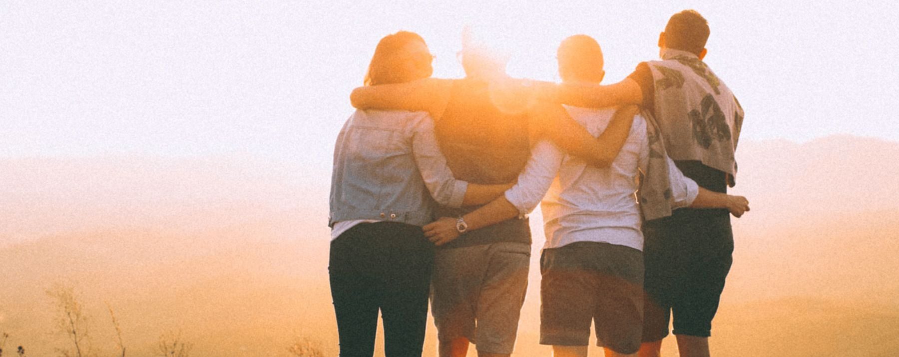 Young adults locking arms looking at the sunset