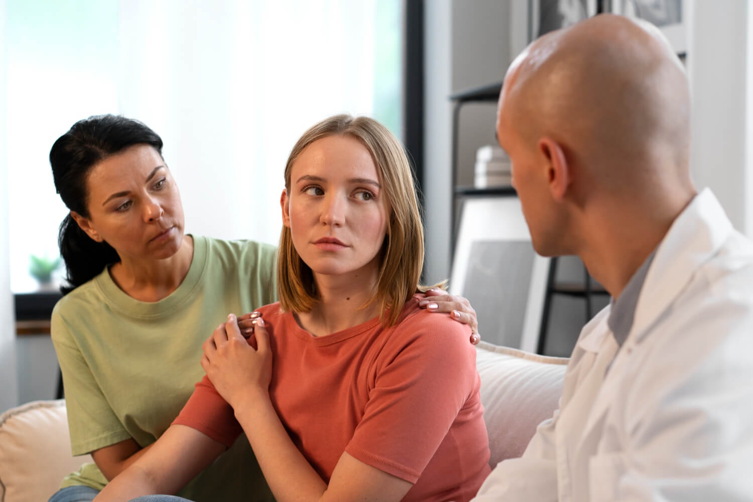 Young woman being comforted by a therapist and her mother