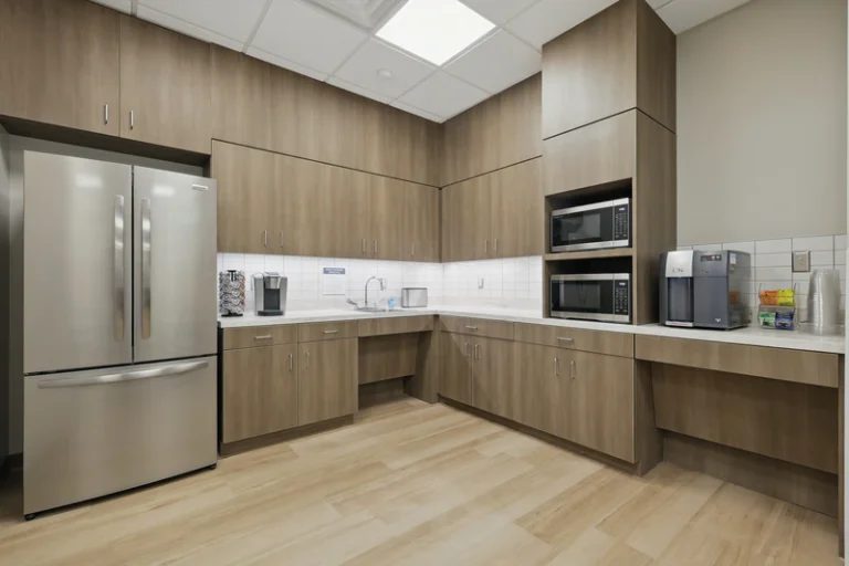Kitchen area with cabinets, refrigerator, microwave, and coffee station