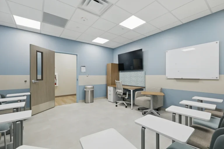 Room with desks, chairs, whiteboard, and presentation screen