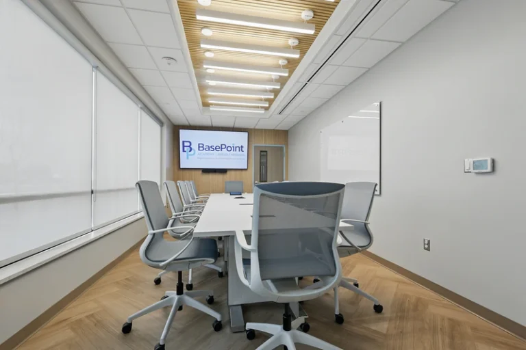 Conference room with table, chairs, and wall-mounted screen