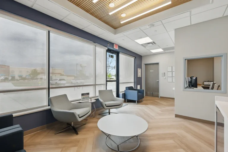 Waiting room with seating, large windows, and reception window