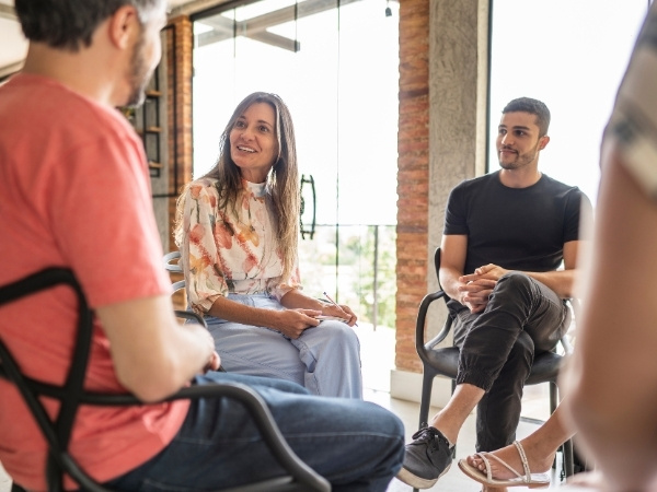 A group therapist smiles while talking to a client