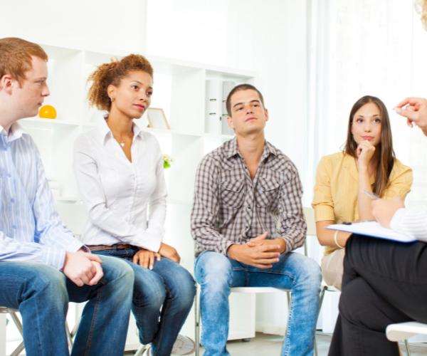Young adults in group therapy listen to their therapist