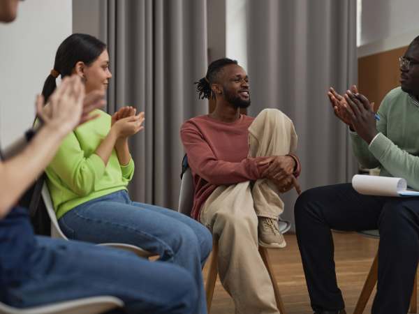 A mental health support group and their therapist applaud a man in attendance