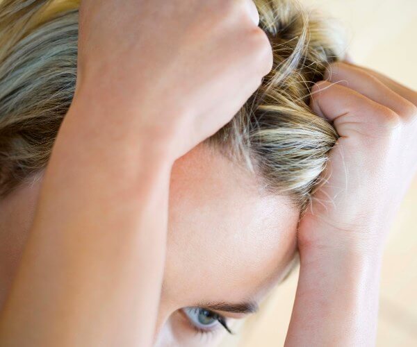 A headshot of a young woman pulling her hair