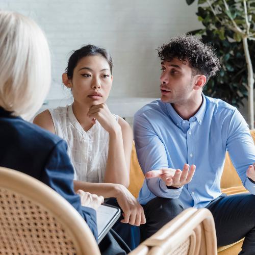 A man talks to his partner as she looks away during a family therapy session