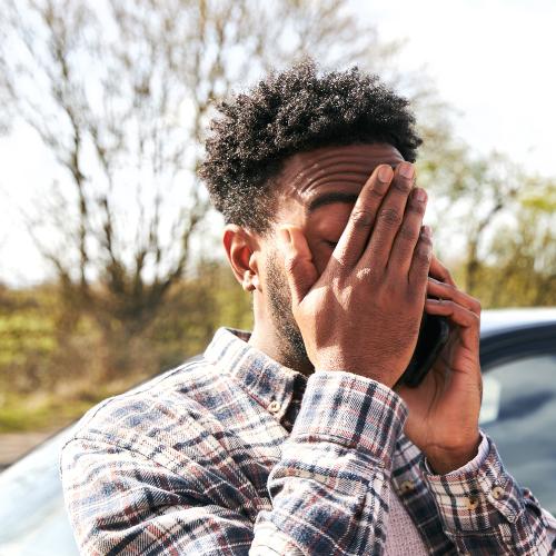 Young man in distress standing outdoors while making a phone call