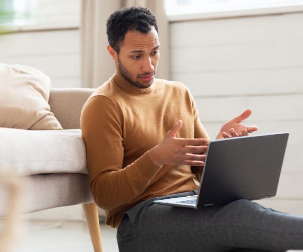 Young man sitting on the floor with his laptop during virtual therapy