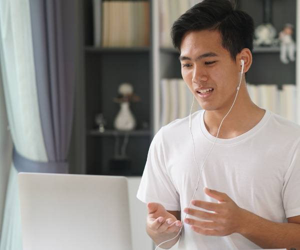 A young man sitting at a desk with his laptop during a virtual therapy session