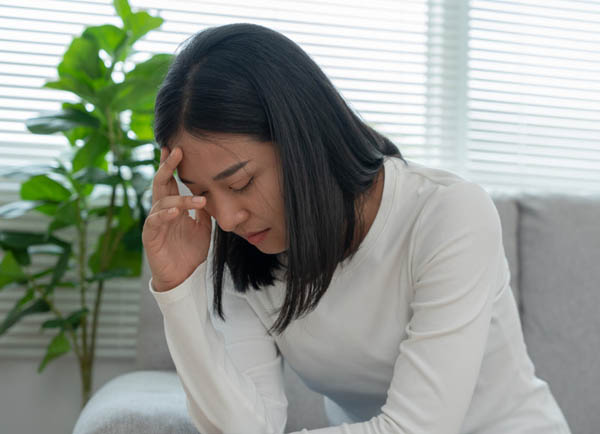 Young woman sitting with her head down in her hand while experiencing a mental health crisis