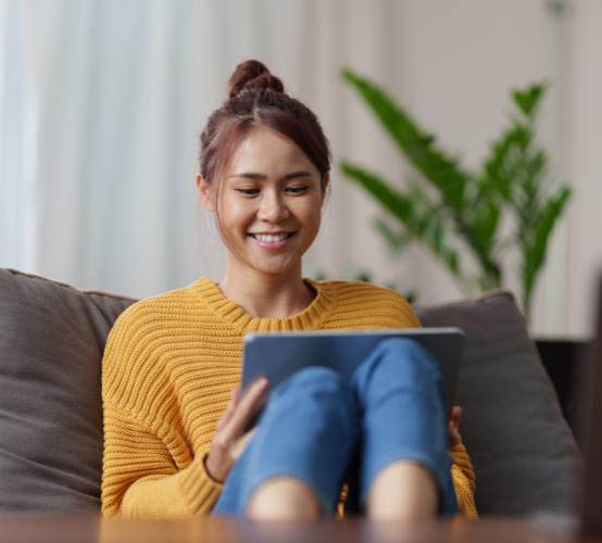 Young woman sitting on a couch and using a tablet for a virtual therapy session