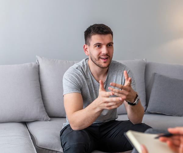 Young man smiling and talking to an unseen mental health therapist