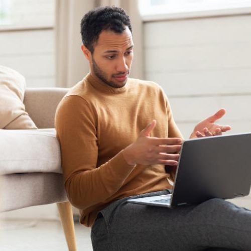 Young man sitting on the floor with his laptop during virtual therapy