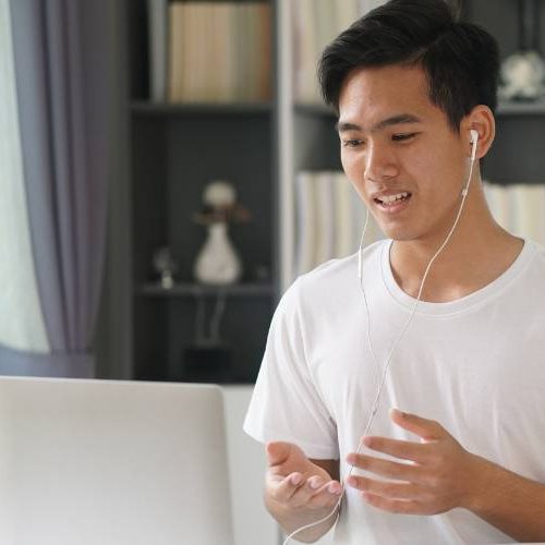 A young man sitting at a desk with his laptop during a virtual therapy session